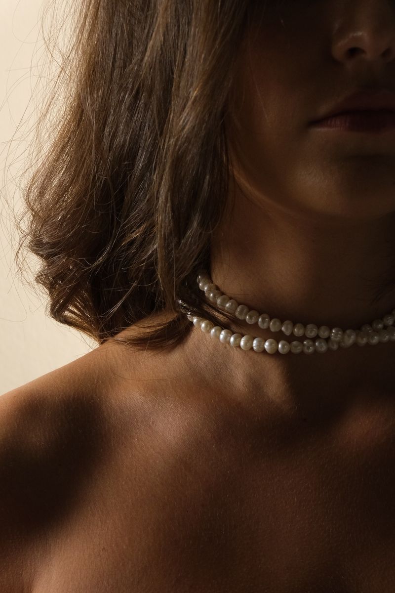 Hals en sleutelbeen met dubbele parelchoker in goudwarm licht