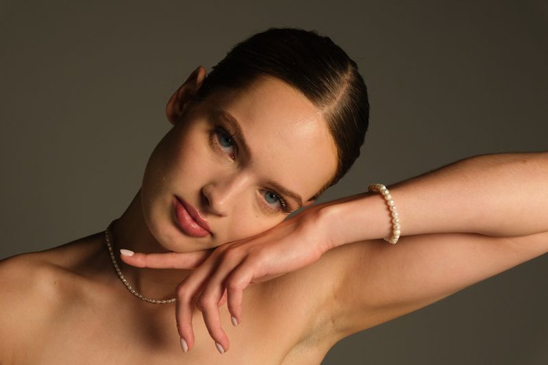Portret met hand tegen het gezicht, ketting en armband